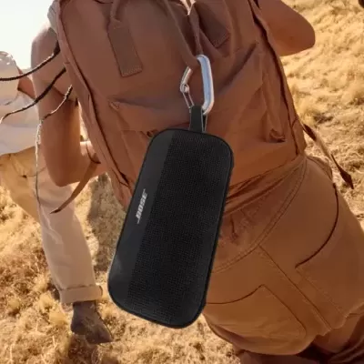 Coluna portátil preta pendurada em mochila castanha ao ar livre