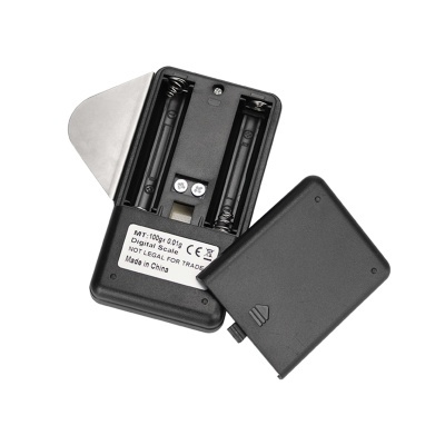 Balança digital preta portátil com tampa removida e compartimento de pilhas visível