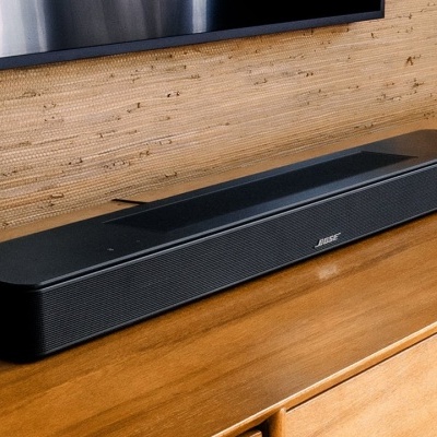 Barra de som Bose preta numa mesa de madeira clara