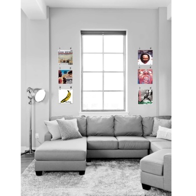 Sala cinzenta com sofá em L, candeeiro e 6 posters coloridos nas paredes ao redor da janela