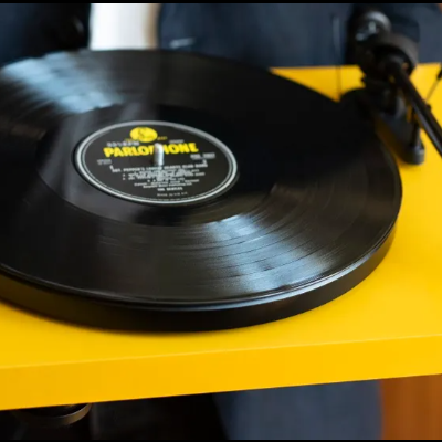 Toca-discos amarelo com disco vinil preto e etiqueta Parrot Now
