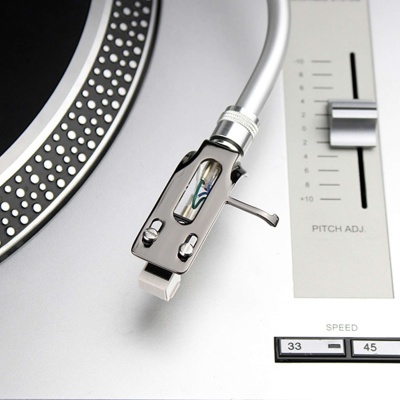 Braço metálico do gira-discos prateado, controlo de velocidade e pitch adj. com escala, parte do disco preto com pontos brancos.