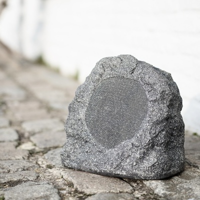 Alto-falante exterior camuflado em pedra cinzenta sobre pavimento de calçada