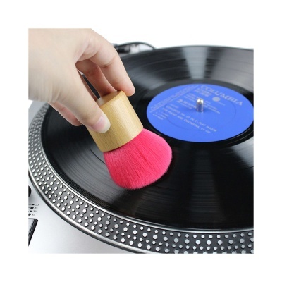 pincel com cabo de madeira a limpar disco de vinil preto numa gira-discos