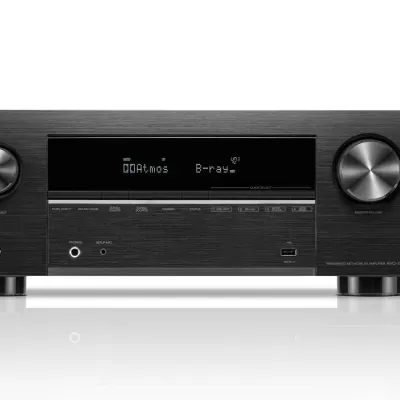 Amplificador multicanal Denon preto com ecrã digital e controlo remoto.