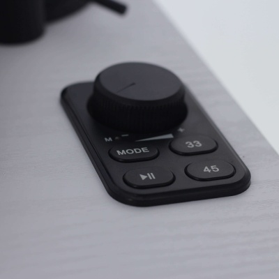 Comando preto com botões MODE, 33, pausa/play, 45 sobre superfície branca