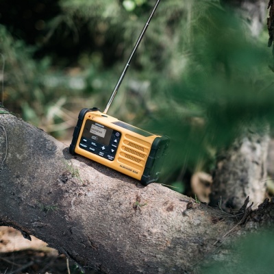Rádio portátil amarelo e preto sobre tronco de árvore na floresta
