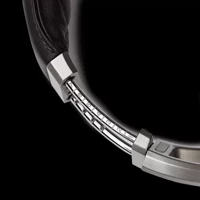 Headphones pretos com estrutura metálica prateada em fundo preto