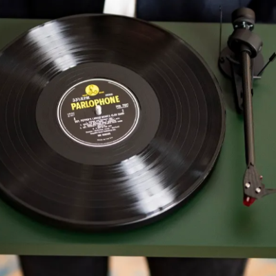 Gira-discos verde-escuro com disco de vinil preto e etiqueta amarela 'PARLOPHONE'