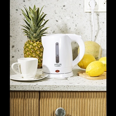 Chaleira elétrica branca ADLER numa bancada de cozinha com chávena, frutas e tomada ao fundo.