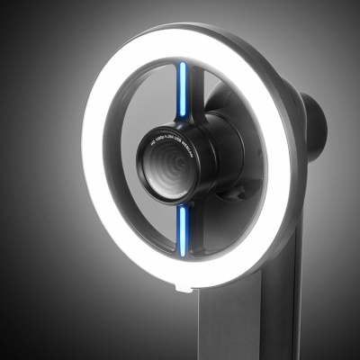 Webcam preta com anel luminoso branco e detalhes azuis em fundo cinza