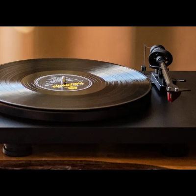 Toca-discos preto com disco vinil preto a tocar sobre superfície de madeira