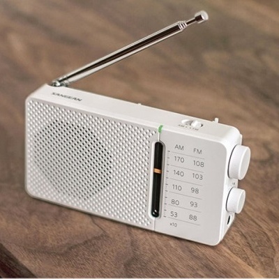 Rádio portátil branco com antena e botões sobre superfície de madeira