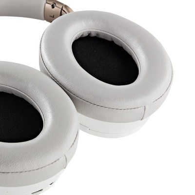 Auscultadores over-ear cinza claro com detalhes em dourado e interior preto