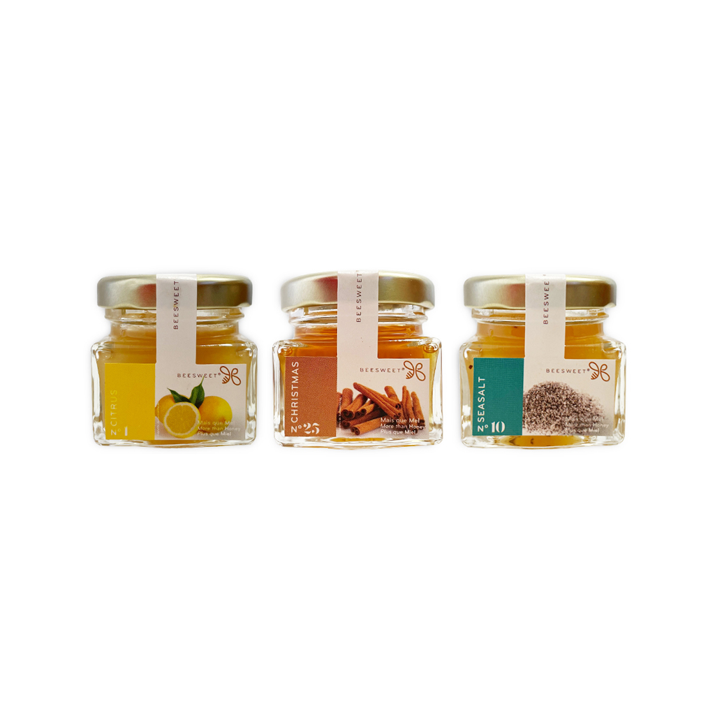Beesweet - Mel sabores 40g Três frascos pequenos de vidro com tampas douradas contendo limão, canela e coentro.