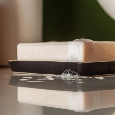 Barra de sabonete branca com espuma sobre saboneteira preta
