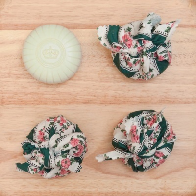 Sabonete branco com coroa e pacotes em tecido floral em madeira