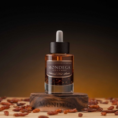 Frasco de azeite MONDEGA com conta-gotas em base de madeira rodeado por frutos secos