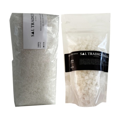 Dois sacos transparentes de plástico com sal grosso e etiquetas branca e preta com texto SAL TRADICIONAL.