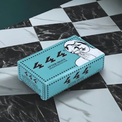 Embalagem azul de after shave 444 sobre azulejos xadrez preto e branco