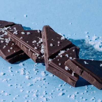 Pedaços triangulares de chocolate negro com sal grosso sobre fundo azul