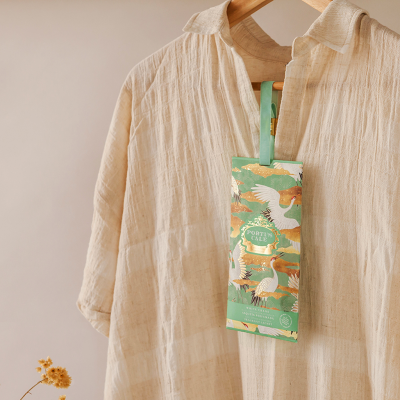 Camisa bege clara pendurada com etiqueta verde ilustrada com aves