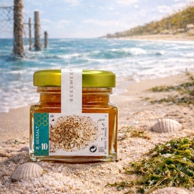 Frasco de mel Seasalt Beesweet na praia com mar ao fundo