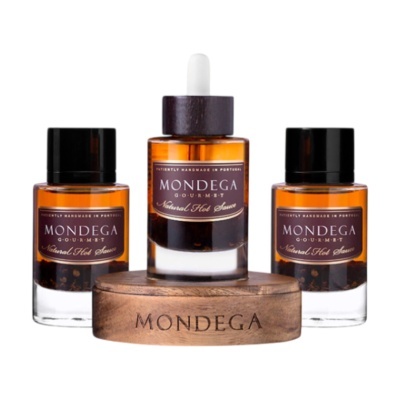 Três frascos de molho em vidro âmbar com rótulo MONDEGA Gourmet e base de madeira