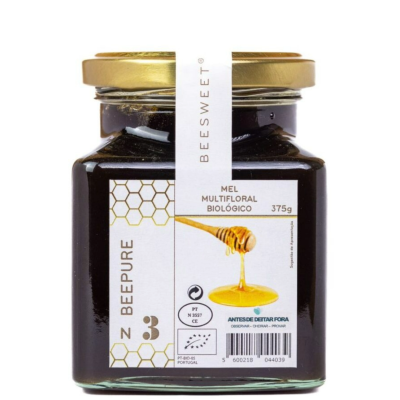 Frasco de vidro com mel multifloral biológico com tampa dourada e etiqueta branca.