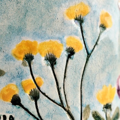 Pintura de flores amarelas com caules pretos sobre fundo azul texturizado
