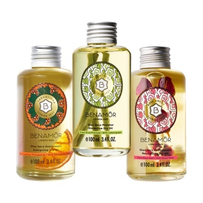Três frascos de óleo seco BENAMÔR com rótulos coloridos e tampas prateadas