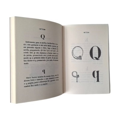 Livro aberto com texto e ilustrações da letra Q em preto e branco