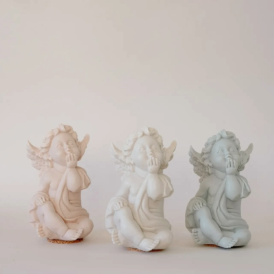 Três estatuetas de anjos sentados em cerâmica com asas e mão na boca