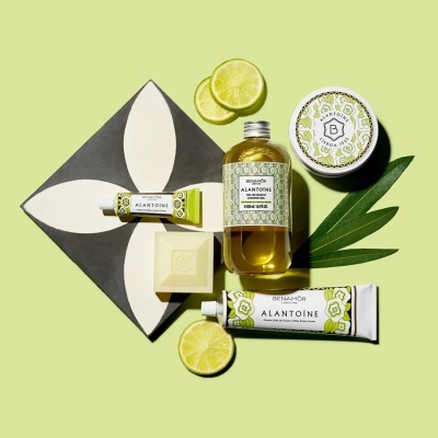 Produtos Benamôr Alantoíne com embalagem floral verde e branca, acompanhados por rodelas de limão e folha verde sobre fundo verde claro.