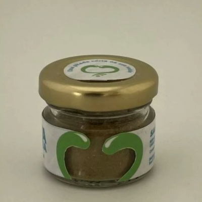 Frasco pequeno de vidro com tampa dourada e rótulo branco com folhas verdes.