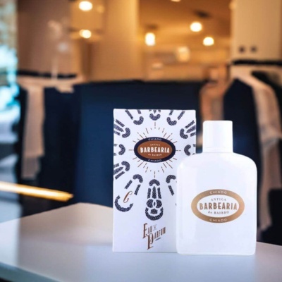 Frasco branco de perfume Antiga Barbearia de Bairro com embalagem ao lado numa mesa