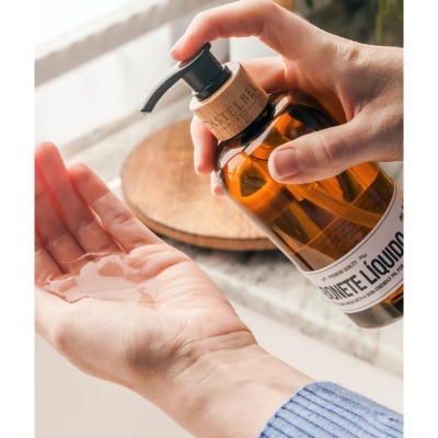 Frasco âmbar com doseador e uma mão a receber líquido