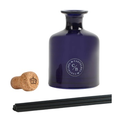 Frasco de vidro azul escuro com tampa de cortiça e palitos de difusor