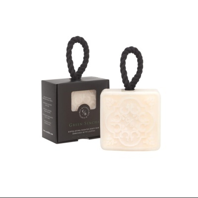 Sabonete quadrado branco com padrão e cordão preto junto a caixa preta