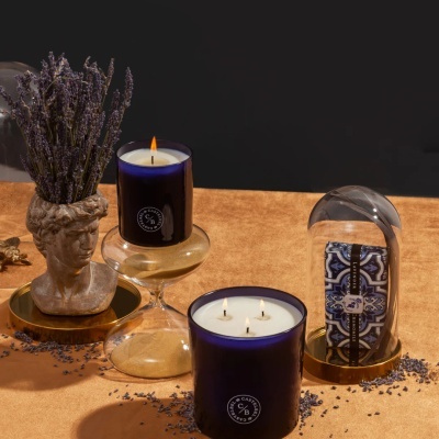 Velas aromáticas, sabonete embalado, busto decorativo com ramos secos sobre superfície laranja