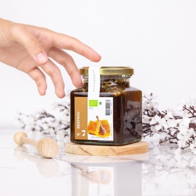 Frasco de vidro com mel escuro e rótulo branco e castanho com favo de mel