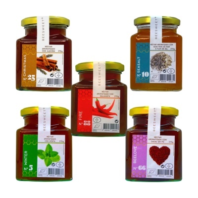 Cinco frascos de néctar aromatizado BEESWEET com tampas amarelas e etiquetas coloridas