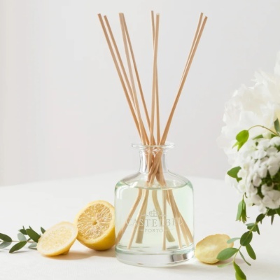 Difusor de aroma em vidro com palitos e limões ao lado