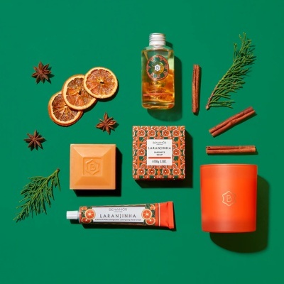 Produtos de beleza BENAMÔR LARANJINHA com elementos naturais sobre fundo verde