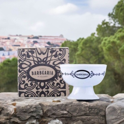 Taça branca com padrão e texto ANTIGA BARBEARIA DE BAIRRO junto a caixa decorada sobre pedra