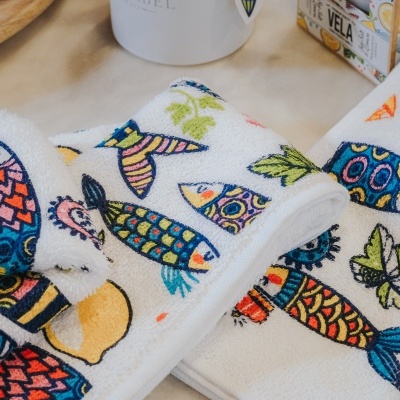 Toalhas brancas com estampas de peixes e folhas coloridas