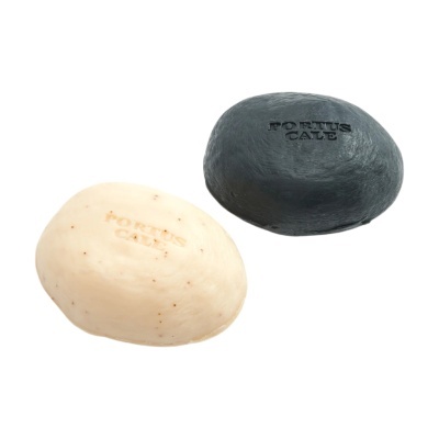 Duas barras de sabão ovais, uma preta e outra bege com partículas, ambas com a gravação PORTUS CALE.