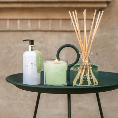 Conjunto de creme, vela acesa e difusor de varetas CASTELBEL PORTO numa mesa preta de metal
