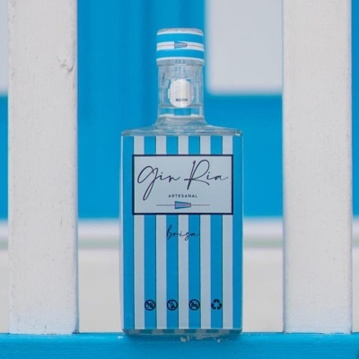 Frasco de gin artesanal com rótulo azul e branco entre varandas brancas