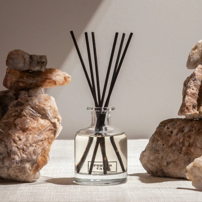 Frasco difusor de aromas em vidro com paus pretos entre pedras decorativas